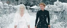 two women dressed in black and white standing next to each other on snow covered ground