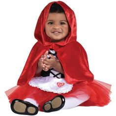 a baby dressed in a little red riding hood and dress up outfit sitting on the floor