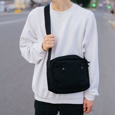 a young man wearing a white sweatshirt and black fanny bag