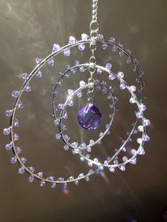 a chandelier hanging from a ceiling with purple beads and a crystal ball in the center