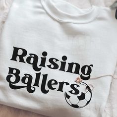 a t - shirt with the words raising ballers on it and a soccer ball