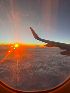 the sun is setting over the clouds as seen from an airplane's window seat