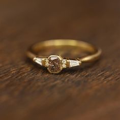 a close up of a gold ring on a wooden table with two diamond rings in the middle