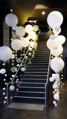 some white balloons are hanging down the stairs