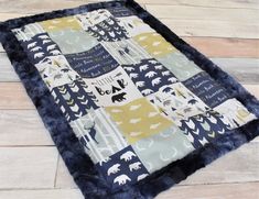 a blue and yellow baby quilt with bears on it's side, sitting on a wooden floor