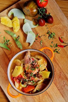 a bowl filled with food sitting on top of a wooden table next to sliced pineapples