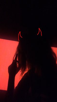 the silhouette of a person with two red eyes on their face, holding a cell phone up to their ear