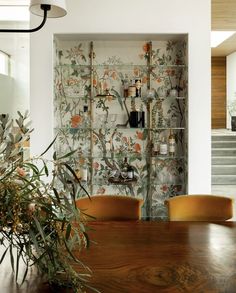 the dining room table is surrounded by yellow chairs and wall papered with orange flowers