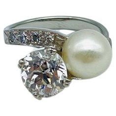 a pearl and diamond ring on a white background