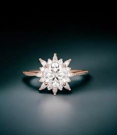 an engagement ring with a flower shaped diamond in the center on a dark background,