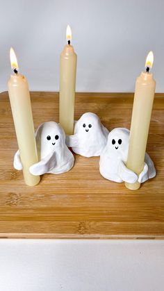 three candles in the shape of ghost heads on a wooden table