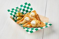 two pieces of pizza in a basket with green and white checkered paper on the table