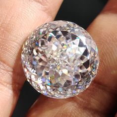 a close up of a person's hand holding a large diamond in their left hand