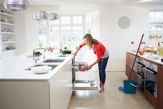 a woman standing in a kitchen with a dishwasher on the counter next to her