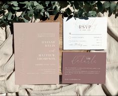 the wedding stationery is laid out next to each other on a bed with greenery