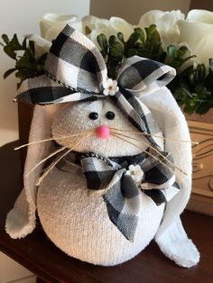 a white stuffed animal with a black and white bow around its neck sitting on a table