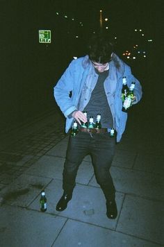 a man standing on the sidewalk holding two bottles