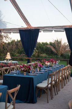 an outdoor dining area with blue table cloths and flowers on the tables set for dinner