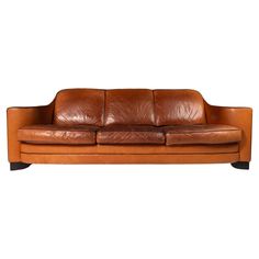 a brown leather couch sitting on top of a white floor next to a wooden frame