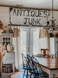 an antique junk sign hangs above a dining room table with chairs and other items on it