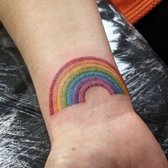 a small rainbow tattoo on the wrist