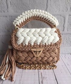 a brown and white handbag sitting on top of a wooden table next to a brick wall