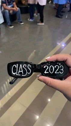 a person holding up a pair of glasses with the word class on it