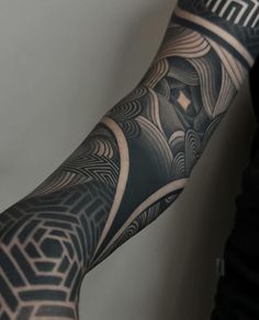 a person with a black and grey tattoo on their arm holding something in his hand