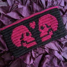 a crocheted wallet with two skulls on it