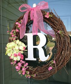 a wreath with the letter r on it and flowers hanging from it's front door