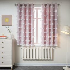 a white radiator sitting next to a window with pink curtains on it's side