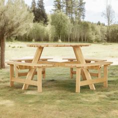 a wooden picnic table sitting on top of a grass covered field