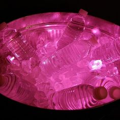 several plastic bottles are in an ice bucket filled with water and ice cubes on a black background