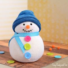 a snowman made out of buttons sitting on top of a wooden table