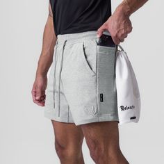 a man in grey shorts holding a white bag