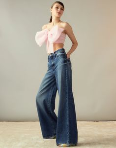 a woman in jeans and a pink top poses for the camera with her hands on her hips