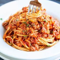 a fork is stuck into spaghetti with meat sauce