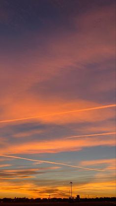 an airplane is flying in the sky at sunset