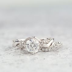 a white gold ring with an oval cut diamond in the center and two smaller round diamonds on each band