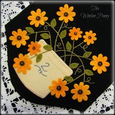 an embroidered purse with flowers on it and a bird in the center, sitting on a lace doily