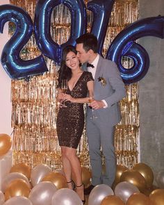 a man and woman standing next to each other in front of balloons that say 2013