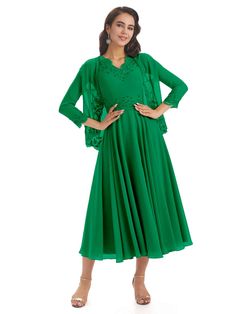 a woman wearing a green dress and matching heels is standing in front of a white background