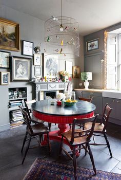 a dining room table with chairs and pictures on the wall above it, in front of a fireplace