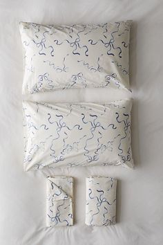 an unmade bed with white sheets and blue swirls on the comforter is shown