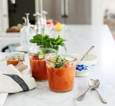 two small jars filled with food sitting on top of a counter next to spoons