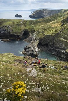 people are camping on the side of a cliff