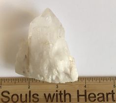 a piece of white rock sitting on top of a ruler with words that read, soul's with heart