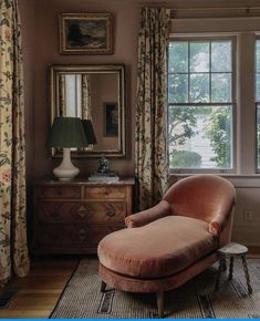 a chair in front of a window with curtains on the windowsill and a lamp next to it