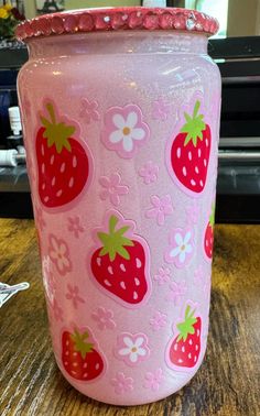 a pink glass vase with strawberries on it