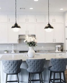 a kitchen with white cabinets and gray stools